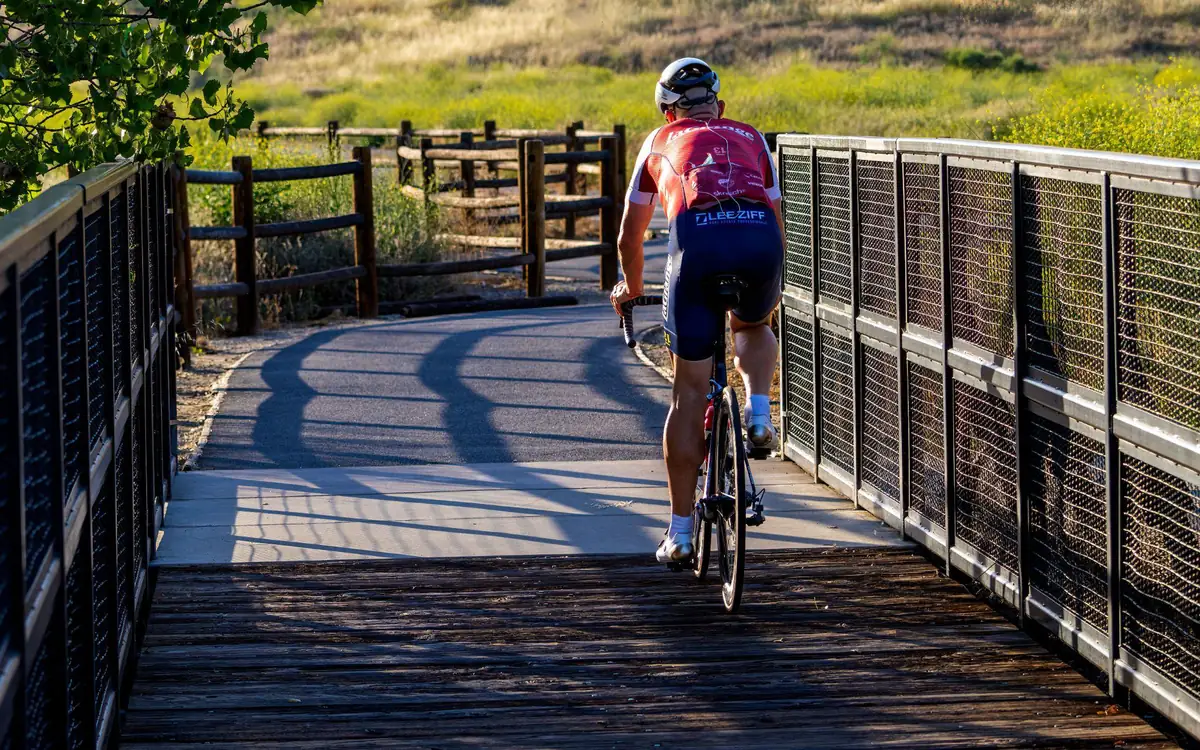 A cyclist riding on a paved Folsom-area trail with railings