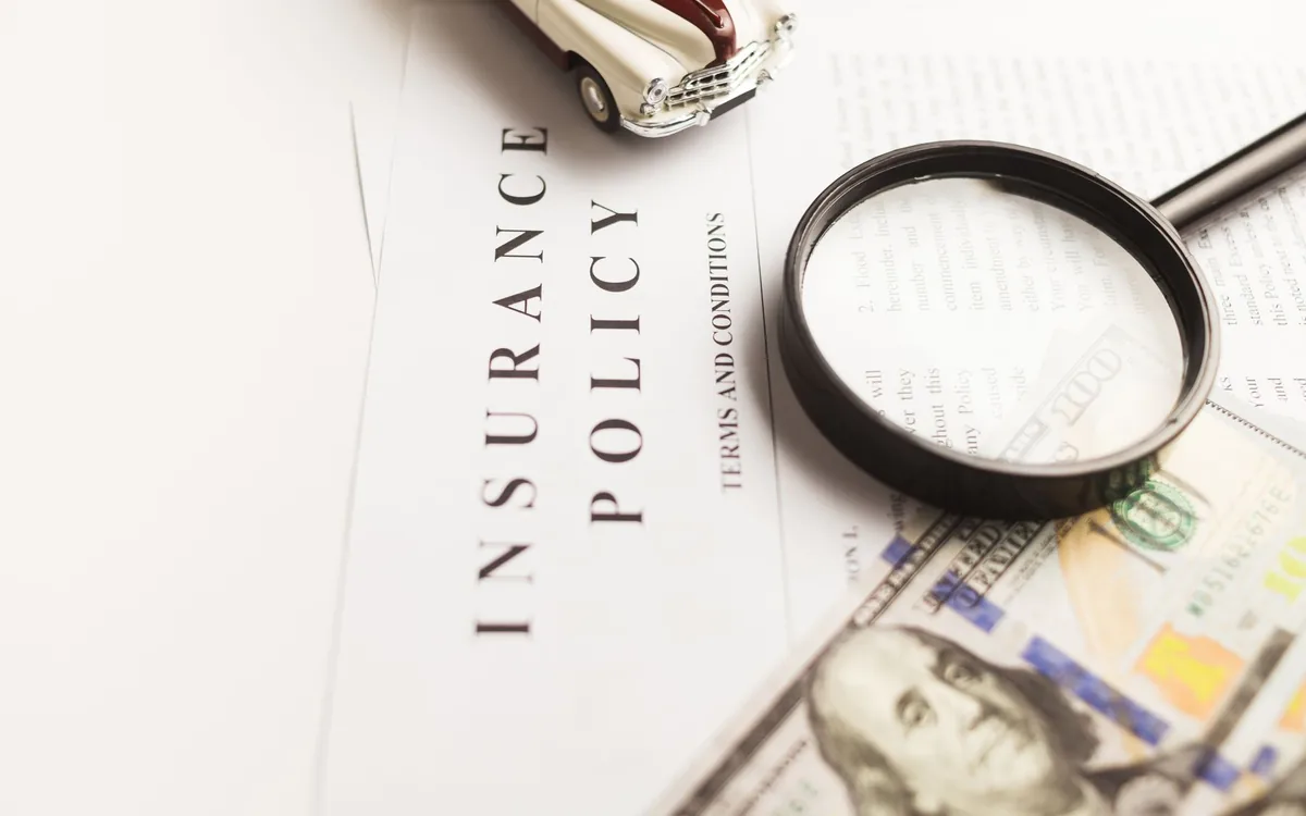 An insurance policy document with a magnifying glass resting on it
