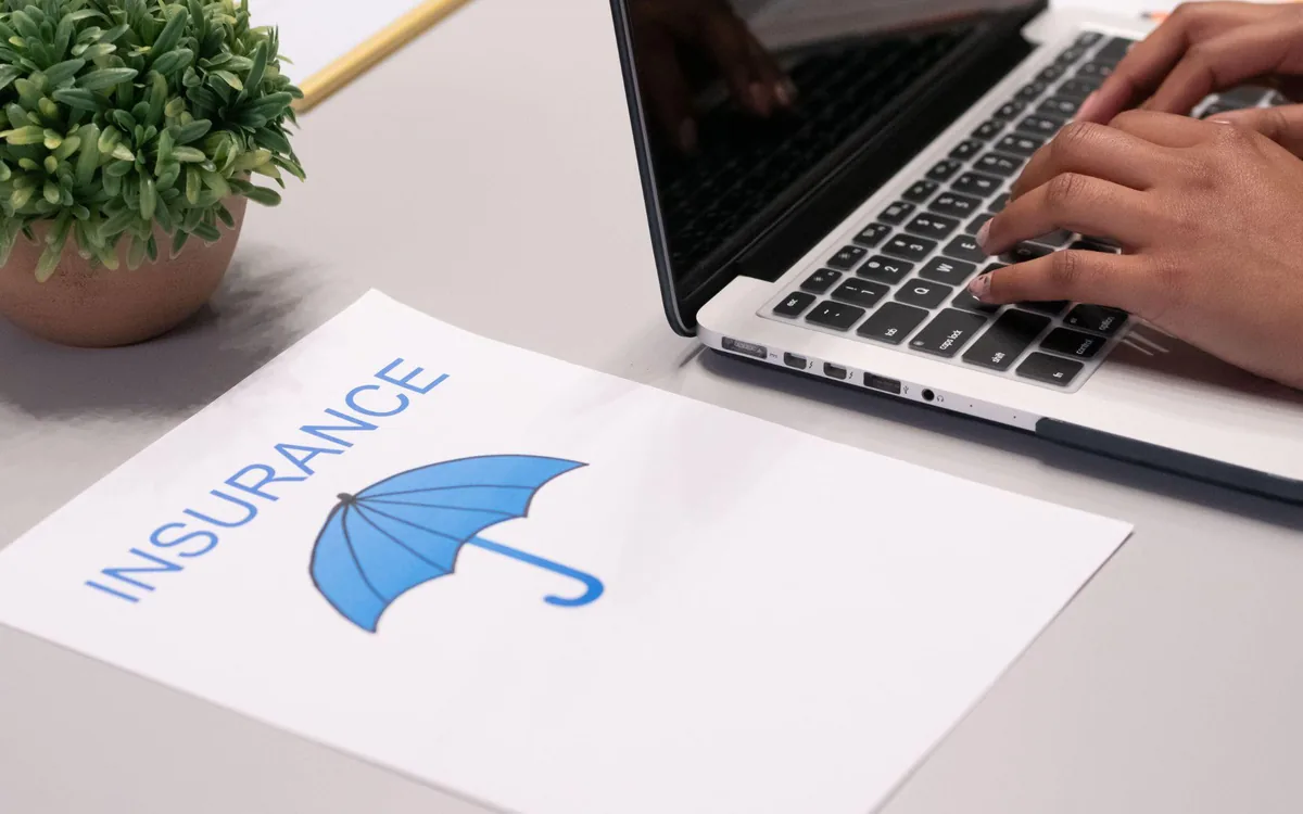 An auto insurance policy document beside a laptop
